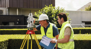Twee landmeters van Sabbe overleggen naast een totaalstation op statief