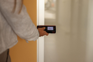 Laserafstandsmeter tegen een deurkozijn tijdens het opmeten van een ruimte