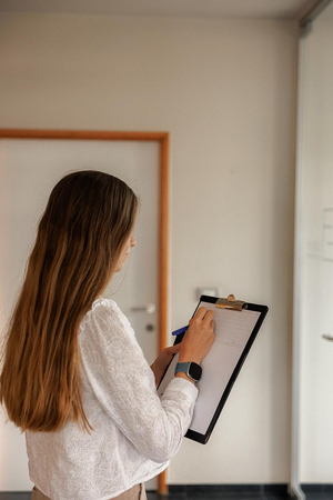 Medewerkster noteert vaststellingen op een klembord tijdens een plaatsbeschrijving in een woning