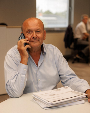 Medewerker van Sabbe telefoneert aan zijn bureau met een stapel dossiers